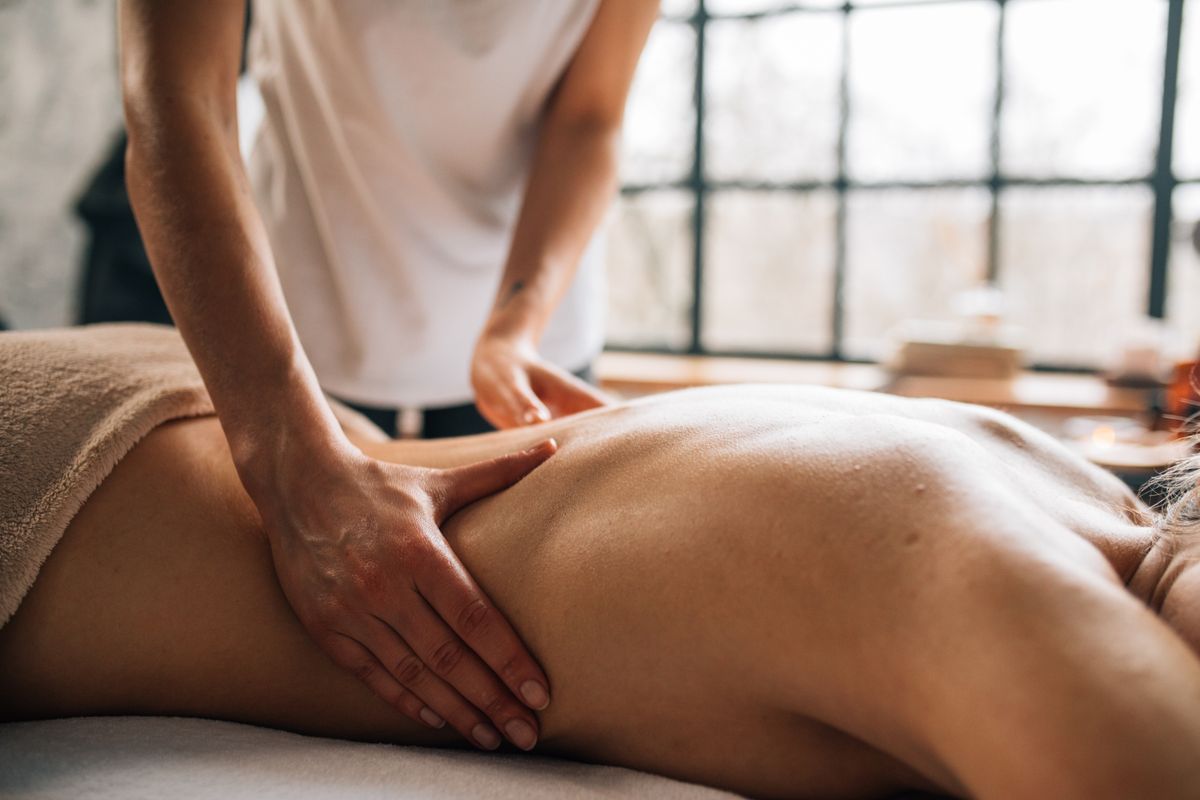 Massage therapist performing a back massage treatment